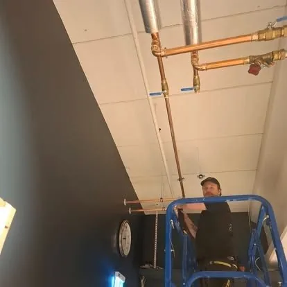 Rørlegger på lift som monterer sprinklerrør under himlingen
