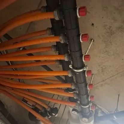 Sprinklerrør med røde tilkoblinger montert langs en betongvegg